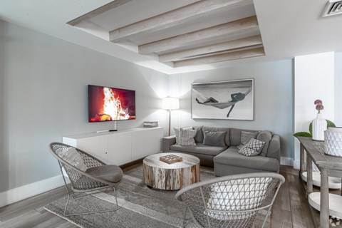 A living room with a grey couch, a coffee table, and a painting on the wall.